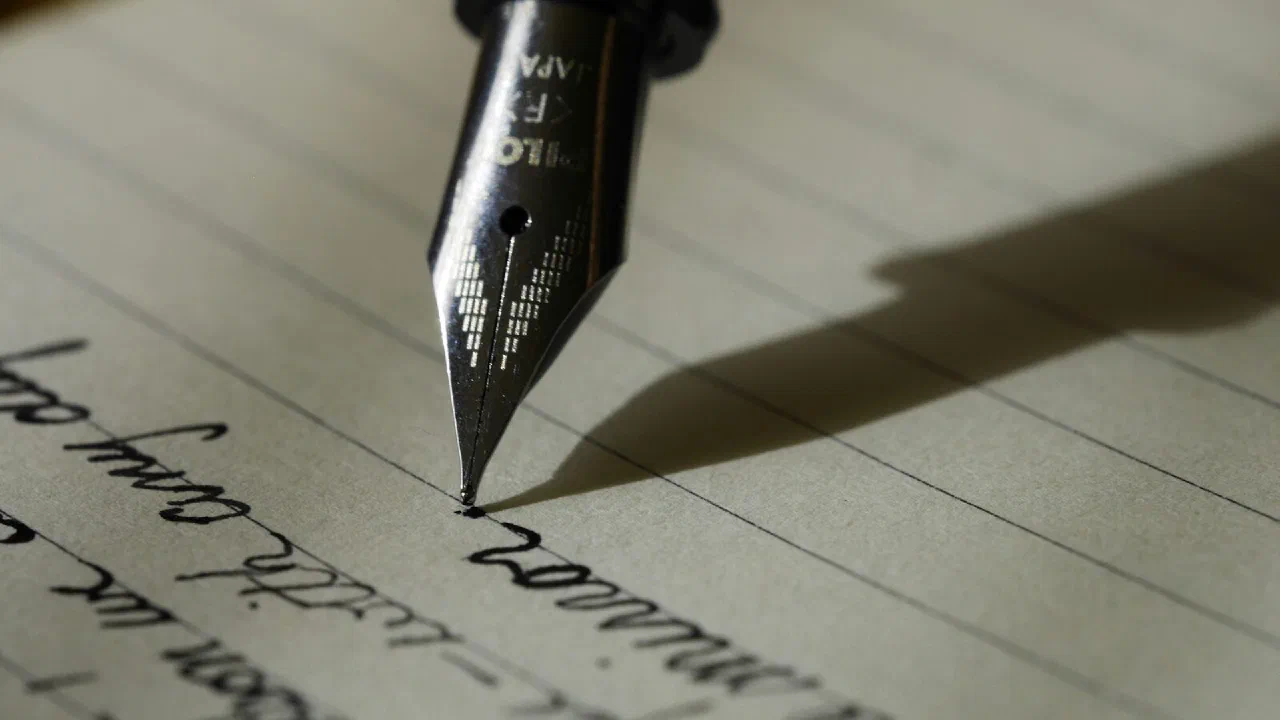 A fountain pen lying across a sheet of lined paper