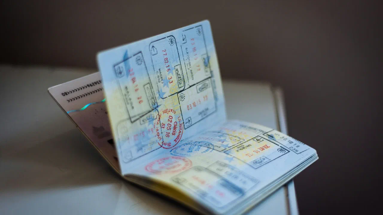 An open passport covered in ink entry stamps, lying on a table